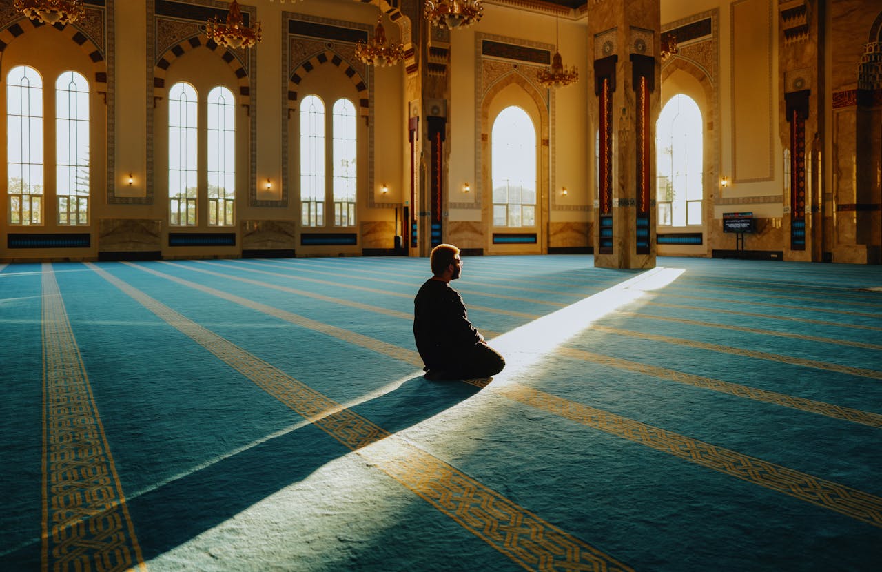 Contact A person in a mosque bathed in sunlight, symbolizing peace and spirituality.