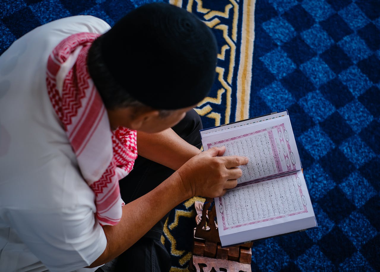 A Muslim man reading the Quran on a rehal inside a mosque, reflecting spirituality.